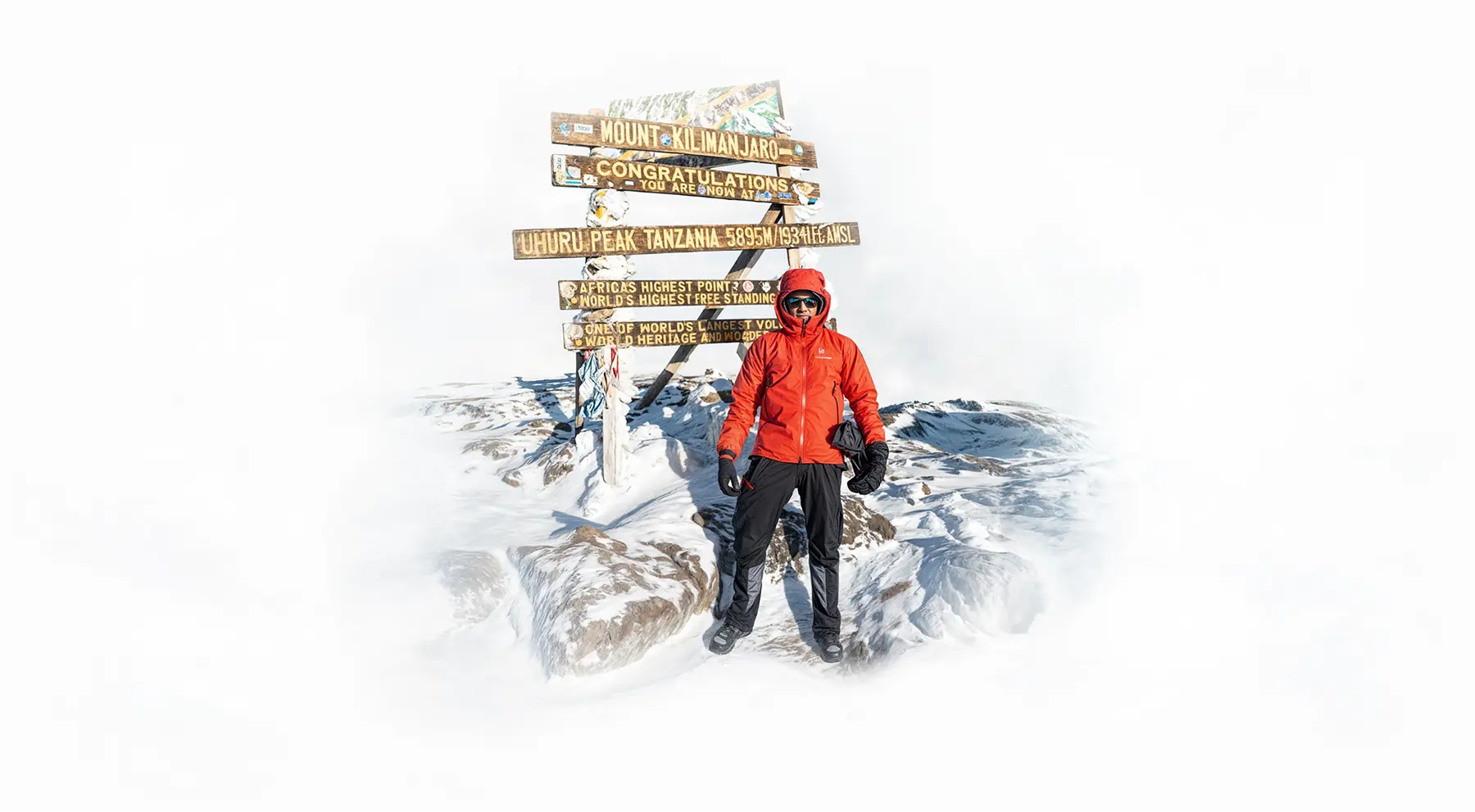 Alpinista junto al cartel de la cumbre Uhuru Peak en el Kilimanjaro Alpinista junto al cartel de la cumbre Uhuru Peak en el Kilimanjaro